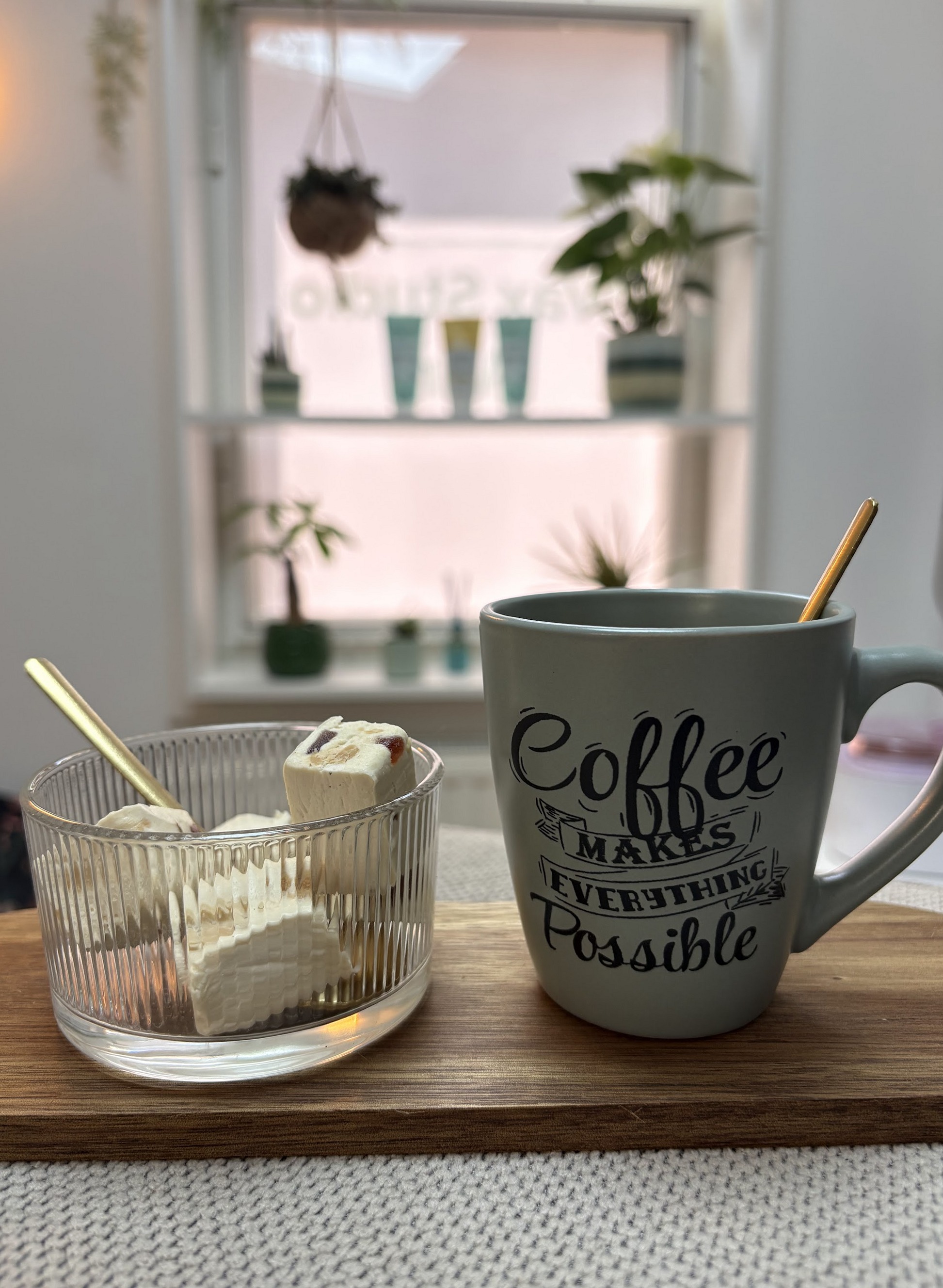 Een houten plankje met een glazen schaal wax en een mok koffie bij het raam van de studio