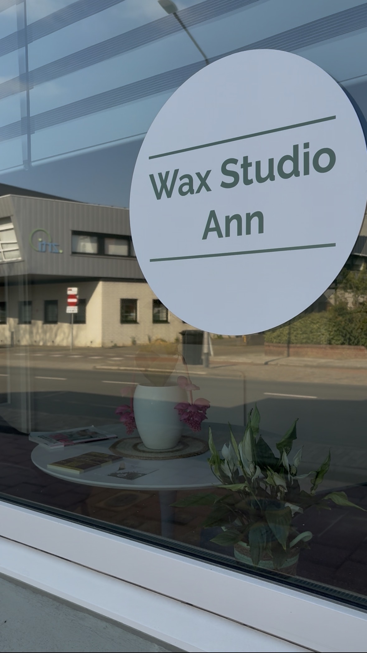 Het raam aan de straat met de ronde sticker Wax Studio Ann